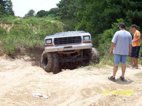 1987 Ford Bronco - Off-road Bronco navigating a steep sandy hill with onlookers present.