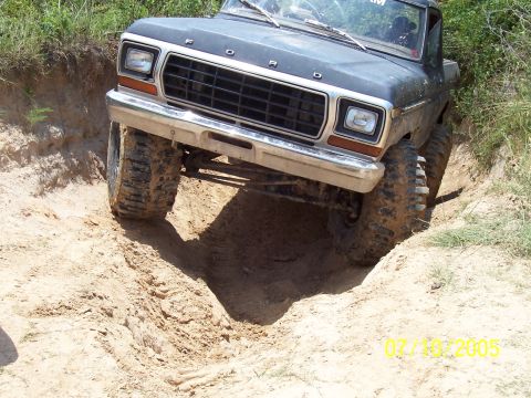 1987 Ford Bronco - This Ford pickup truck is shown off-roading on a dirt track with significant terrain variation.