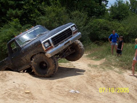 1987 Ford Bronco - Modified pickup truck navigates a challenging off-road course with spectators watching.
