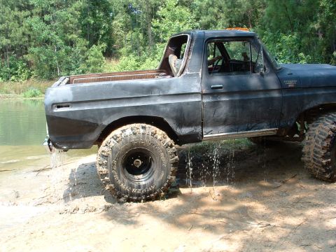 1993 Ford Bronco - This classic Ford Bronco is partially submerged in mud and water, with water dripping from its undercarriage.