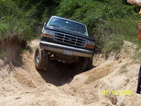 1987 Ford Bronco - A black 1992 Ford Bronco navigates a steep dirt trail with its front wheels turned.