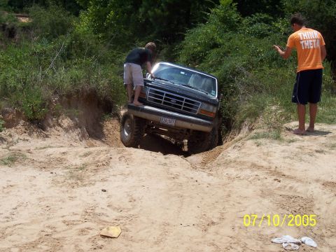 1987 Ford Bronco - A black Ford Bronco navigates a challenging sandy terrain with onlookers present.