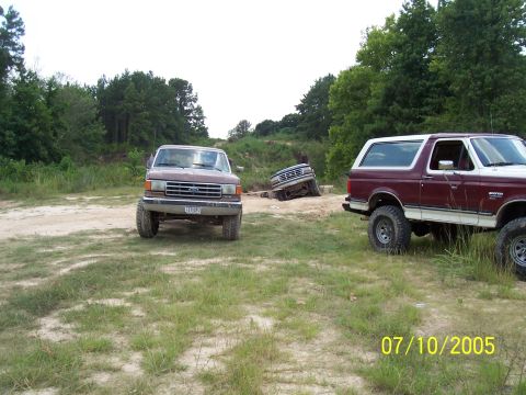 1987 Ford Bronco - Three off-road vehicles are seen in a dirt lot on July 10, 2005, with one Bronco appearing to be stuck.