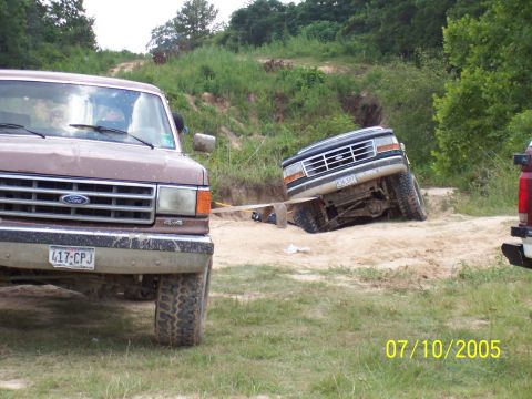 1987 Ford Bronco - Two Ford trucks navigate a challenging off-road course on a sunny day.