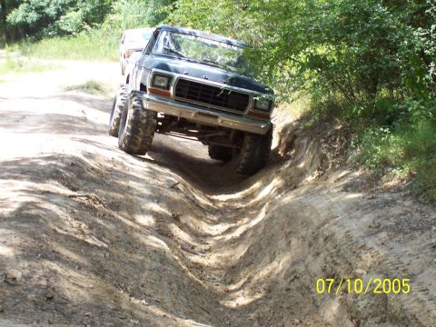 1987 Ford Bronco - Off-road adventure with a lifted Ford Bronco navigating a challenging dirt path.