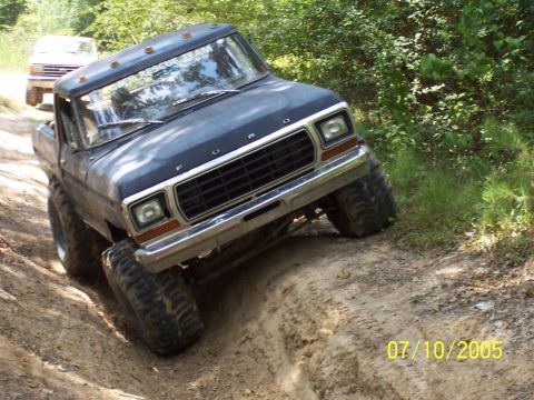 1987 Ford Bronco - A Ford truck navigates a dirt trail with a second vehicle following behind.