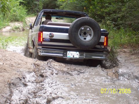1987 Ford Bronco - This 1987 Ford Bronco is navigating a muddy trail, showing its rear end and spare tire.