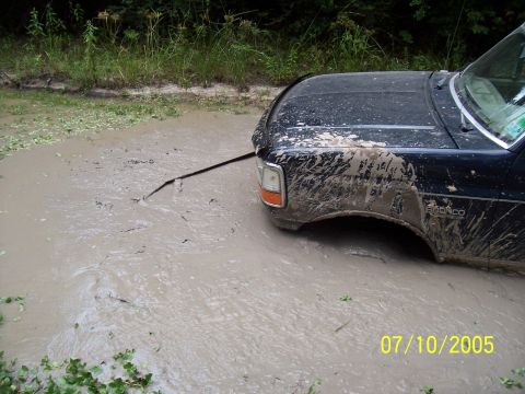 1987 Ford Bronco - A black 1987 Ford Bronco is stuck in a muddy puddle on a dirt road.