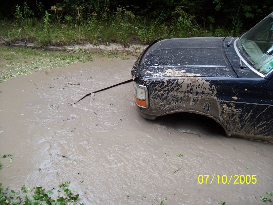 Black 1987 Ford Bronco stuck in mud, front quarter view