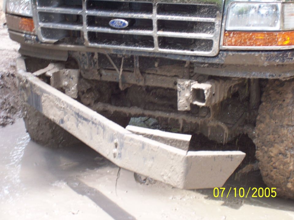 Front bumper and grille of a muddy Ford truck stuck in mud