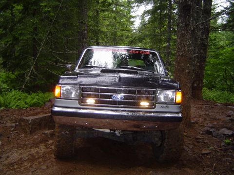 1989 Ford Bronco - This Ford truck, likely from the late 1980s, navigates a muddy, wooded trail.