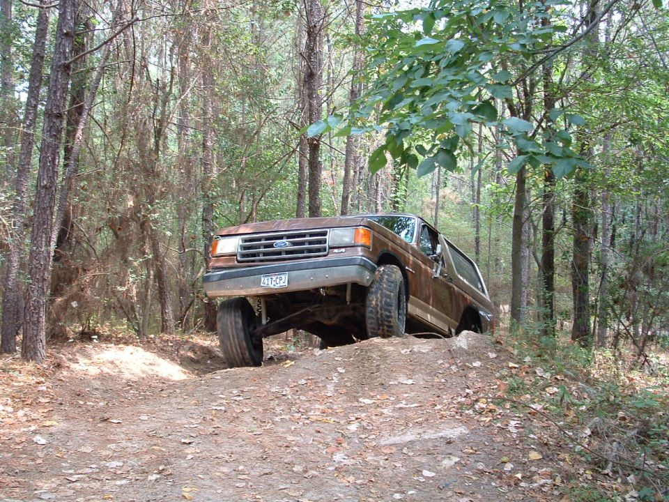 Brown Ford Bronco on dirt hill, front left wheel lifted