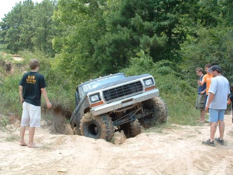 1993 Ford Bronco - A lifted Ford truck is stuck in a muddy ditch while onlookers observe the situation.