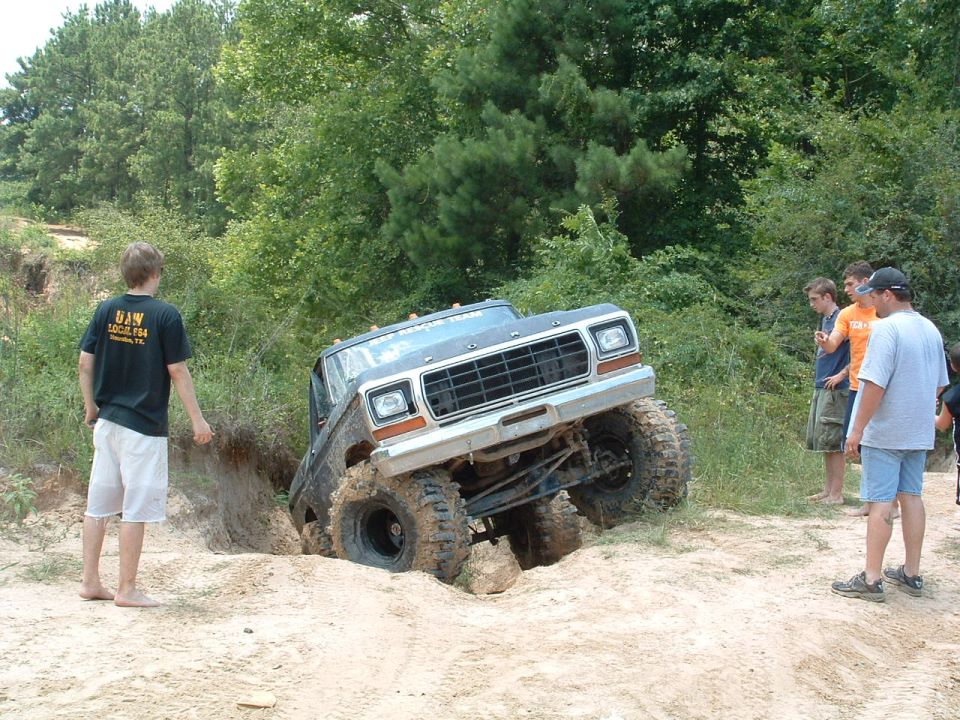 Ford F-Series truck stuck in a ditch off-road, with people watching