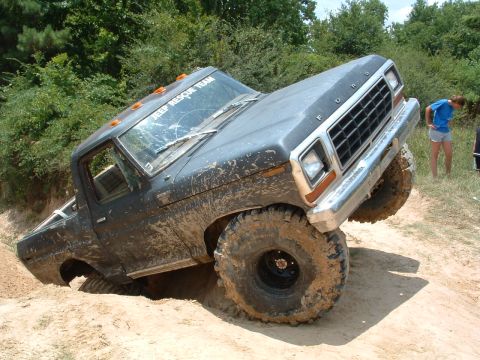 1993 Ford Bronco - This heavily modified Ford truck is navigating a challenging off-road course, with its front end tilted upwards.