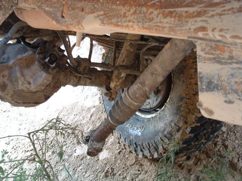 1993 Ford Bronco - Close-up of the undercarriage of a heavily soiled off-road vehicle, focusing on the rear axle and suspension components.