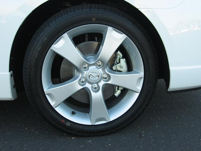 Silver five-spoke wheel with Mazda logo on white car