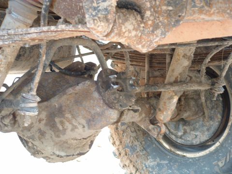 1993 Ford Bronco - Close-up of the rear axle and suspension parts, heavily covered in dirt and rust.