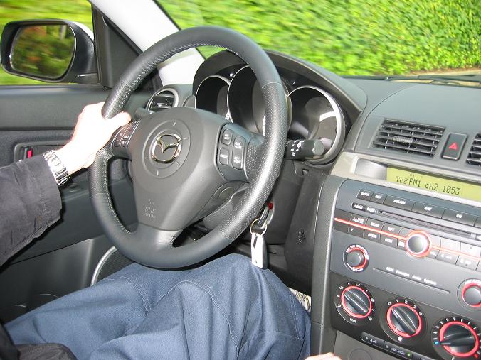 Car interior with a hand on the steering wheel, showing the dashboard and radio display