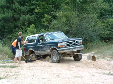 1993 Ford Bronco - Ford Bronco stuck in sand, people attempting to dig it out.