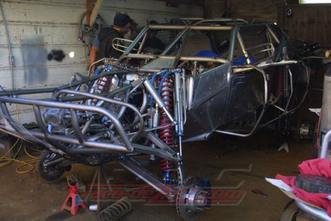 1990 Ford Bronco - Tube-frame off-road buggy under construction in a garage, showing extensive long-travel coilover suspension and bare chassis.