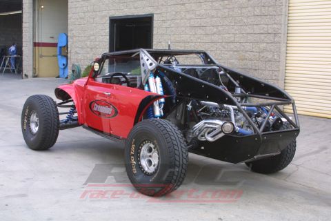 1990 Ford Bronco - Rear three-quarter view of a red VW-bodied off-road buggy revealing its exposed engine and welded tube chassis.