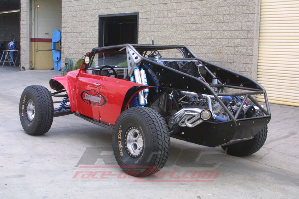 Rear view of red VW Beetle off-road buggy showing exposed engine and tube chassis in a shop