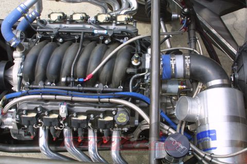 1990 Ford Bronco - Detailed engine-bay shot of a V8 with blue silicone hoses, braided fuel lines and a polished intake manifold.