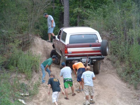 1993 Ford Bronco - A 1993 Ford Bronco navigates a steep dirt incline with assistance from several people.