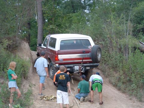 1993 Ford Bronco - People help a 1993 Ford Bronco navigate a steep dirt incline during an off-road excursion.