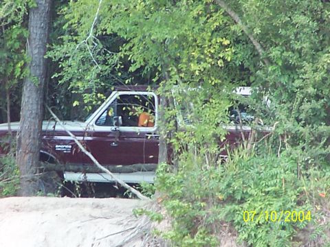 1987 Ford Bronco - A maroon and white Ford Bronco is partially obscured by foliage, with a date stamp indicating it was photographed in 2004.