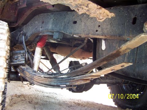 1987 Ford Bronco - The underside of a vehicle is shown, focusing on the suspension components and frame structure.