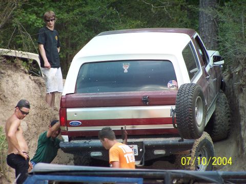 1987 Ford Bronco - A group of friends attempts to free a maroon and white Ford Bronco from a muddy ditch.