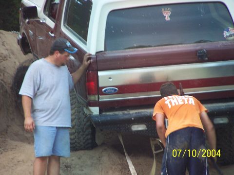 1987 Ford Bronco - Two men attend to a maroon and white 1987 Ford Bronco stuck in sand.