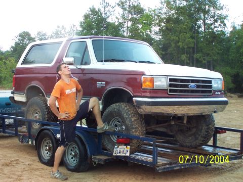 1987 Ford Bronco - A man poses next to a lifted 1987 Ford Bronco on a trailer.