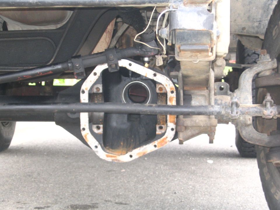 Underside view of a solid front axle differential housing with cover and tie rods
