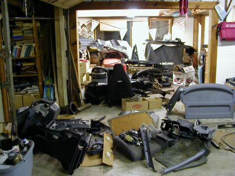 1994 Ford Probe - Disassembled car interior parts are scattered across the floor of a messy garage.