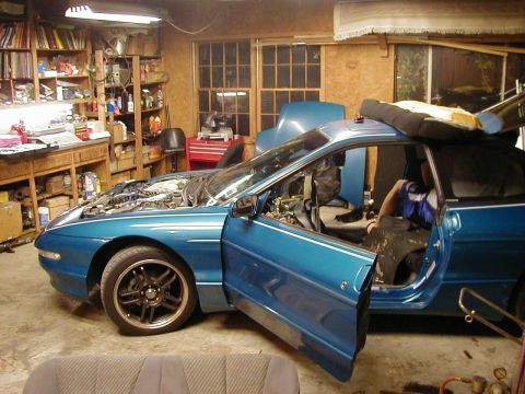 1994 Ford Probe - A blue 1994 Ford Probe sits in a garage with its hood and doors open, revealing its interior and engine bay.