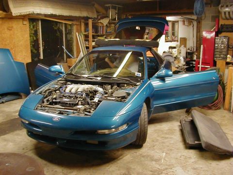 1994 Ford Probe - 1994 Ford Probe in a garage, hood and driver's door open, engine visible.
