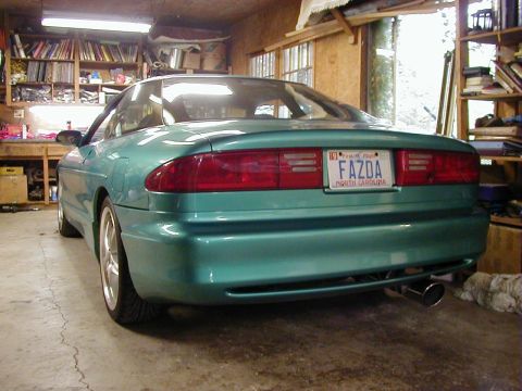 1994 Ford Probe - Rear view of a teal coupe parked indoors. The license plate reads 'FAZDA'.