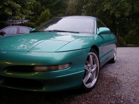 1994 Ford Probe - A green 1994 Ford Probe is parked outside on a gravel driveway with trees and foliage in the background.