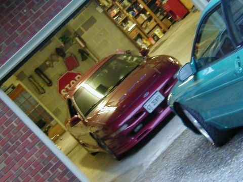 1994 Ford Probe - Two cars are parked inside a garage, with shelves full of items in the background.