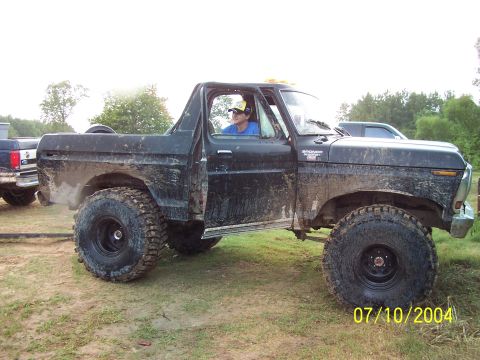 1987 Ford Bronco - This mud-covered Ford Bronco is parked off-road with another vehicle in the background.