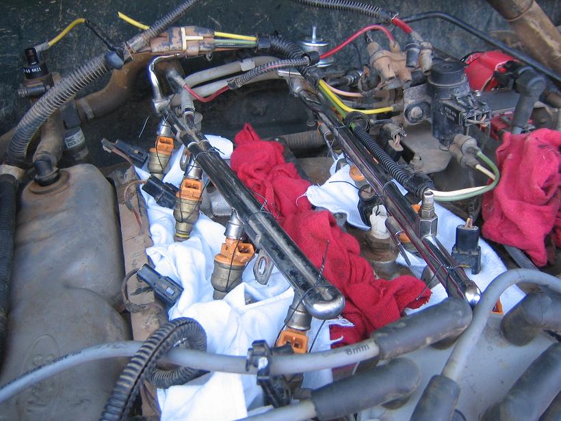 Ford V8 fuel rails and injectors laid over the intake valley on shop rags