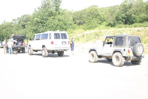 2003 Jeep TJ - Two modified vehicles, a Jeep TJ and a van, are parked on a dirt road with people around.