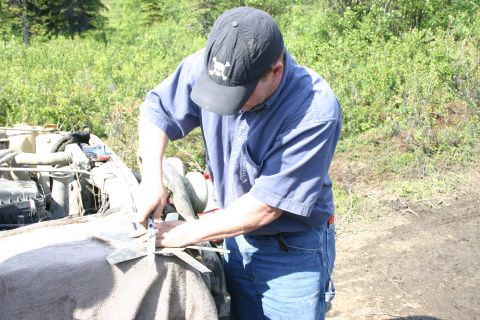2003 Jeep TJ - Man works on the engine of a 2003 Jeep TJ outdoors.