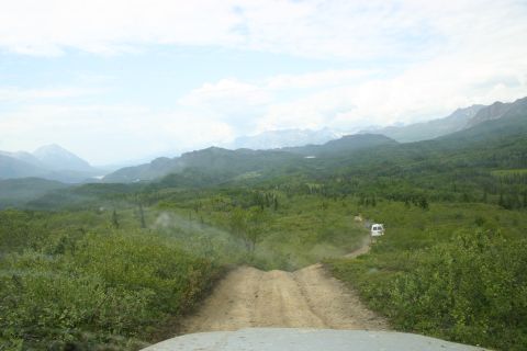 2003 Jeep TJ - A view from a vehicle driving down a dirt road in a mountainous, forested area.