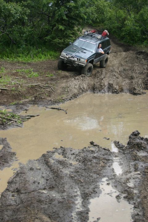 2003 Jeep TJ - A Jeep navigates a challenging muddy obstacle course on an off-road trail.