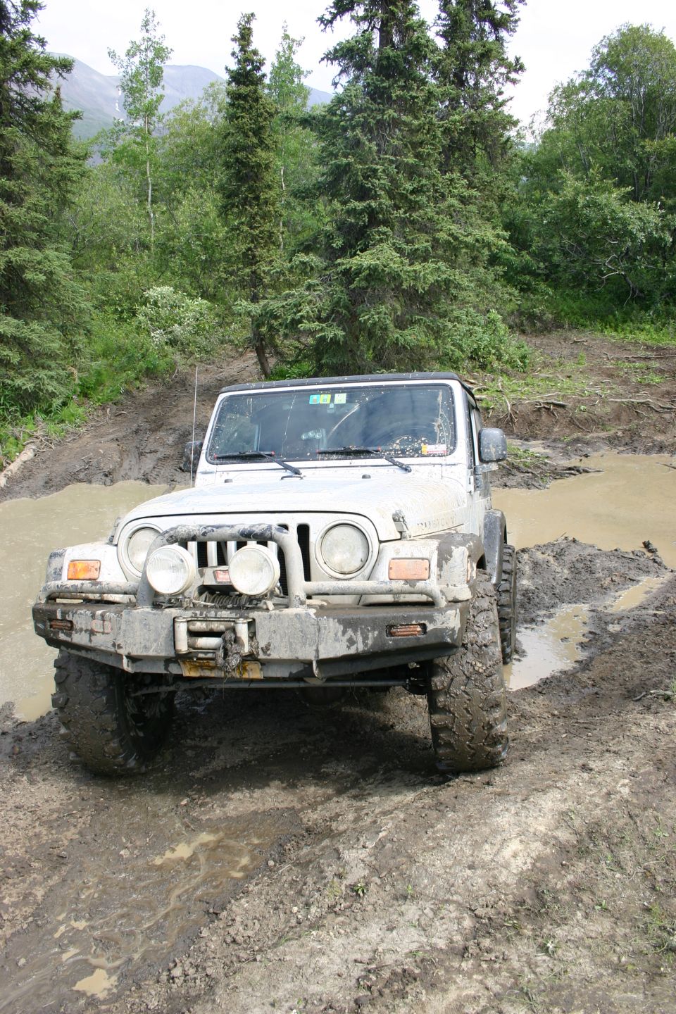 2003 Jeep TJ driving through a muddy trail, front view