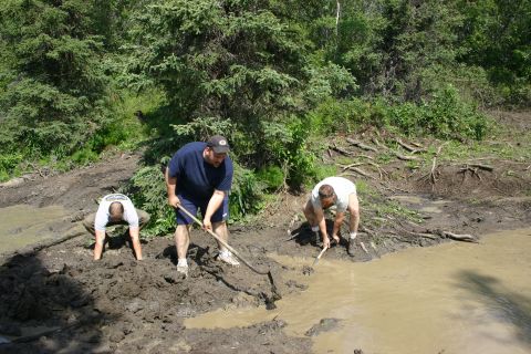 2003 Jeep TJ - Men digging in a muddy area near trees.